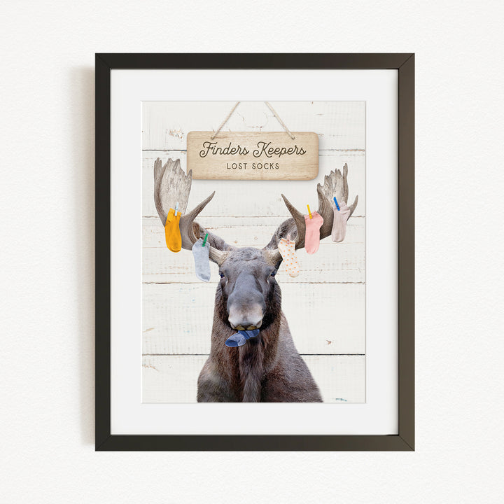A framed image of a moose with a sign that says "Finders Keepers Lost Socks" hanging above it.