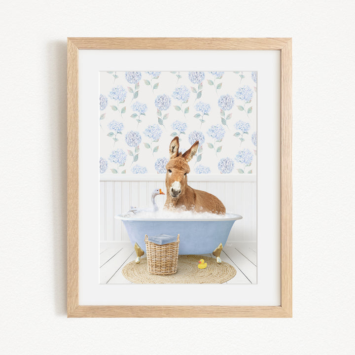 A donkey is sitting in a blue bathtub filled with bubbles, surrounded by various bath toys, including rubber ducks and a goose.