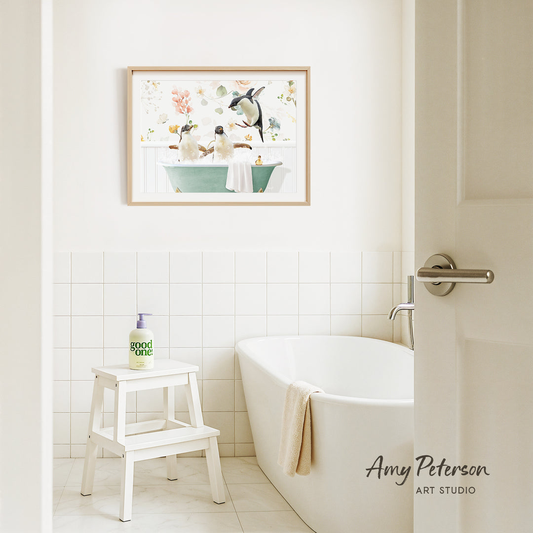 A bathroom with a white bathtub, a stool, and a framed picture of penguins in a bathtub on the wall.