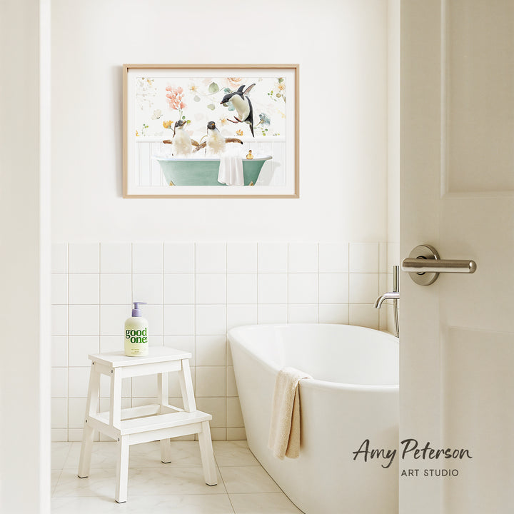 A bathroom with a white bathtub, a stool, and a framed picture of penguins in a bathtub on the wall.