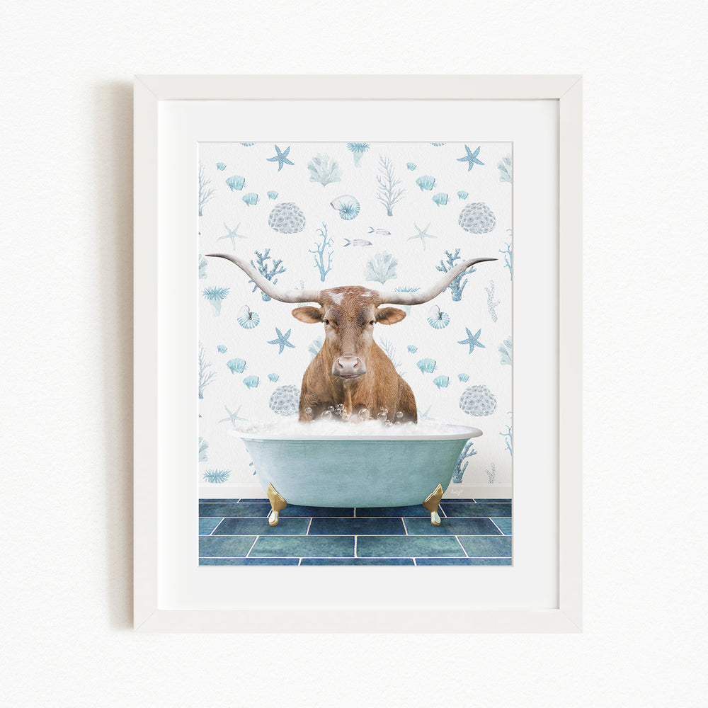 A framed image depicting a brown cow with large horns sitting in a bathtub filled with bubbles, surrounded by a blue and white ocean-themed background.