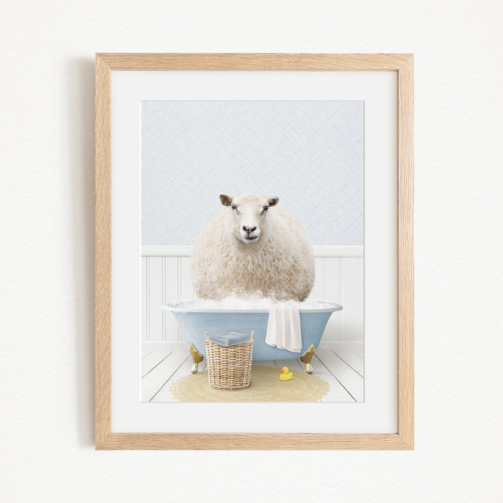 A fluffy white sheep sits in a blue bathtub filled with bubbles, surrounded by a yellow rubber duck and a basket.