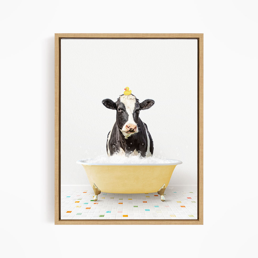 A black and white cow is sitting in a yellow bathtub filled with water, with a yellow rubber duck perched on its head.