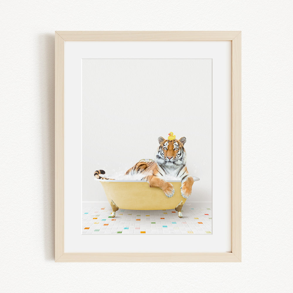 A tiger is sitting in a yellow bathtub filled with bubbles, wearing a yellow hat and looking directly at the camera.