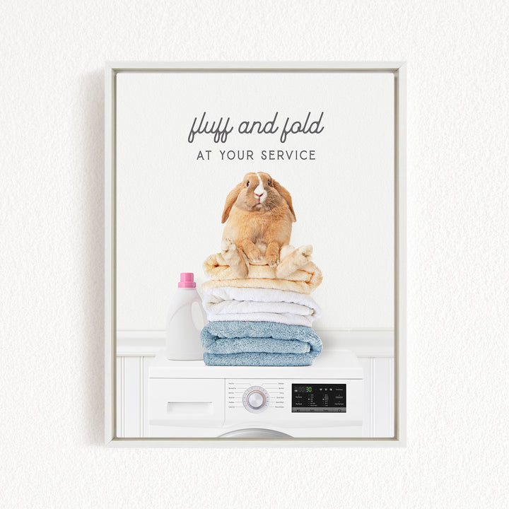 A white washing machine with a stack of folded towels on top, and a bottle of laundry detergent next to it.