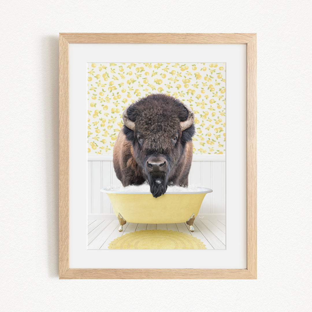 A buffalo is sitting in a yellow bathtub, with a yellow and white floral pattern on the wall behind it.