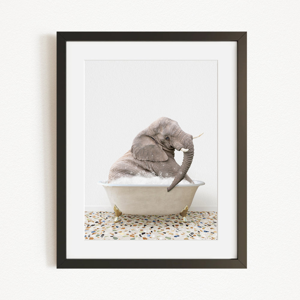 A gray elephant sitting in a white bathtub filled with water, with its trunk submerged in the water.