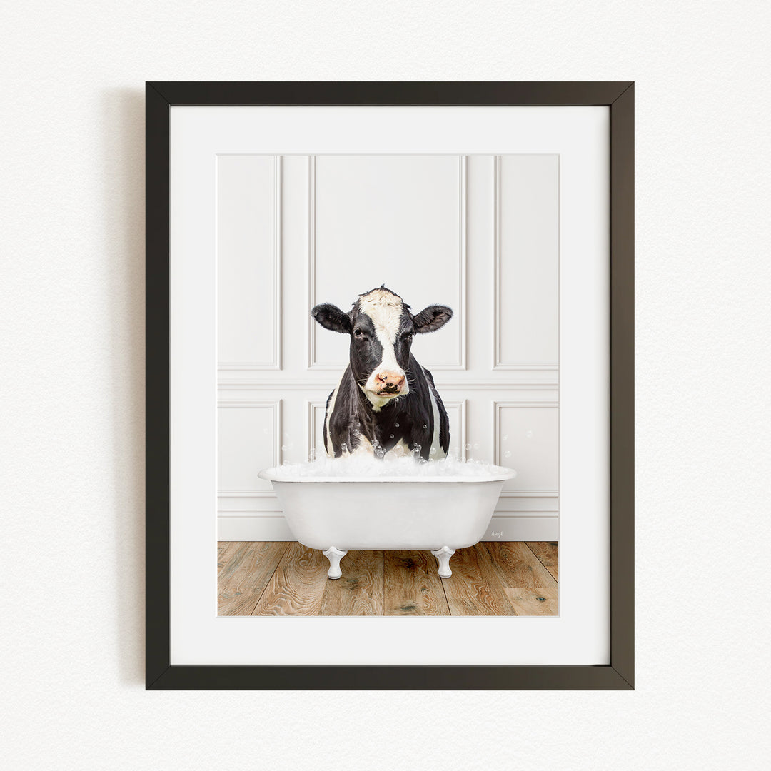 A black and white cow is sitting in a white bathtub filled with water, creating a whimsical and humorous scene.