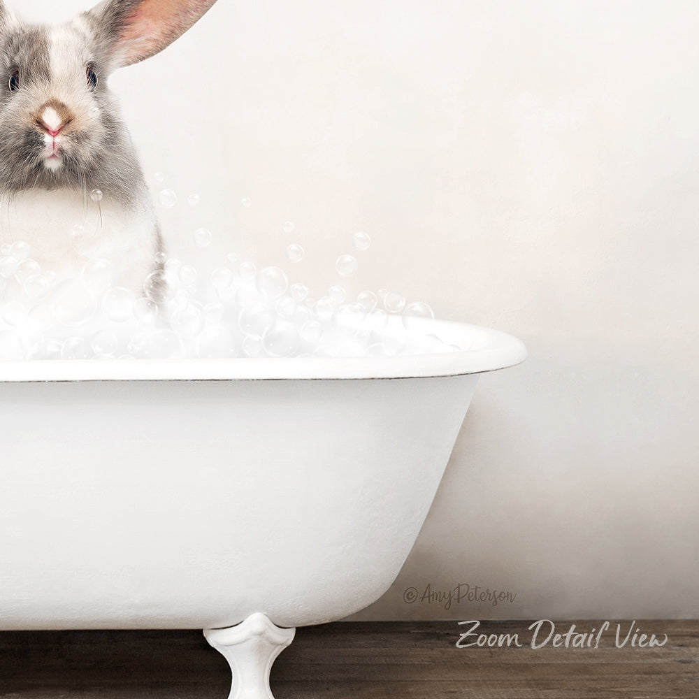 A fluffy white rabbit sitting in a white bathtub filled with bubbles, looking directly at the camera.