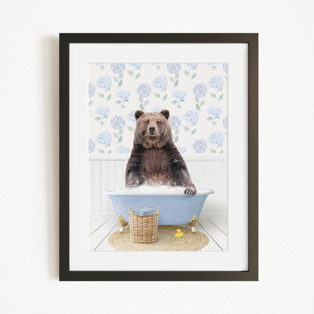 A brown bear sitting in a blue bathtub filled with water, surrounded by a floral patterned wall and a basket of rubber ducks.