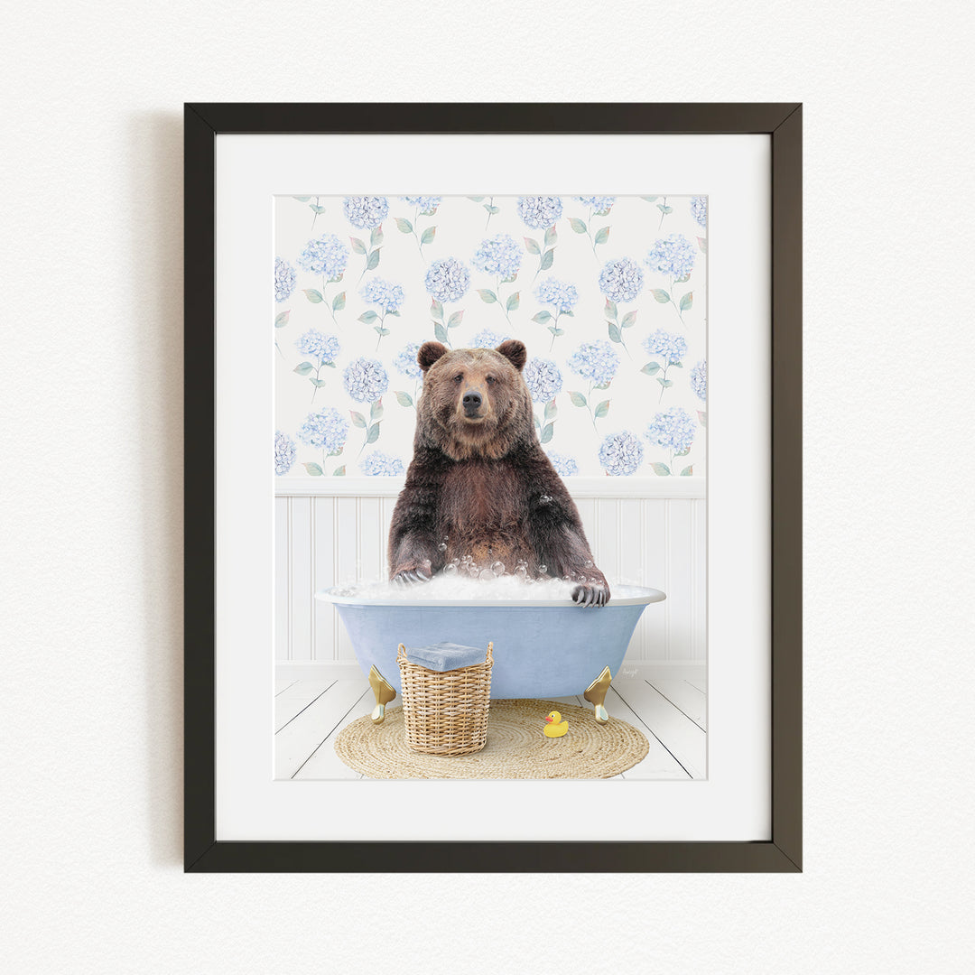 A brown bear sitting in a blue bathtub filled with water, surrounded by a floral patterned wall and a basket of rubber ducks.
