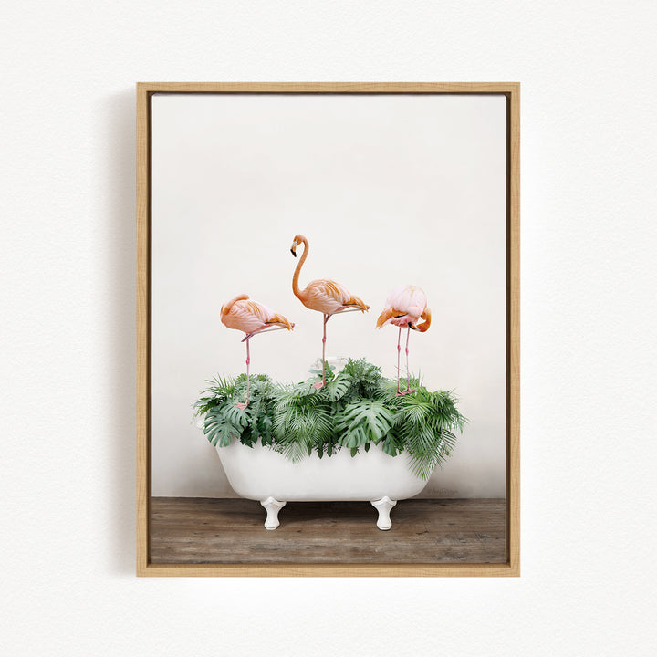 A framed image depicting three pink flamingos standing on a white bathtub filled with green plants.