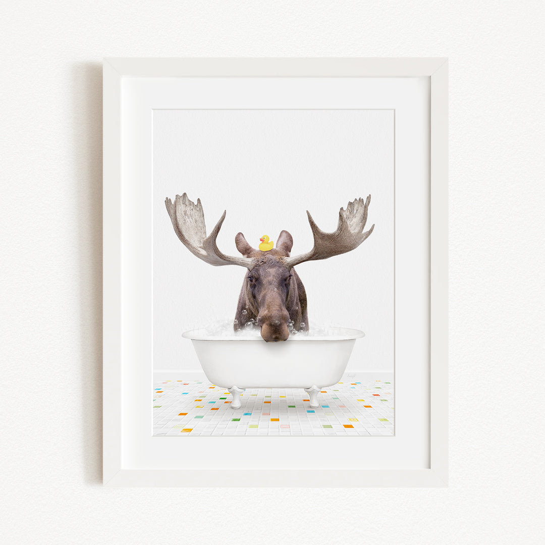 A moose with large antlers is sitting in a white bathtub, with a yellow rubber duck perched on its head.