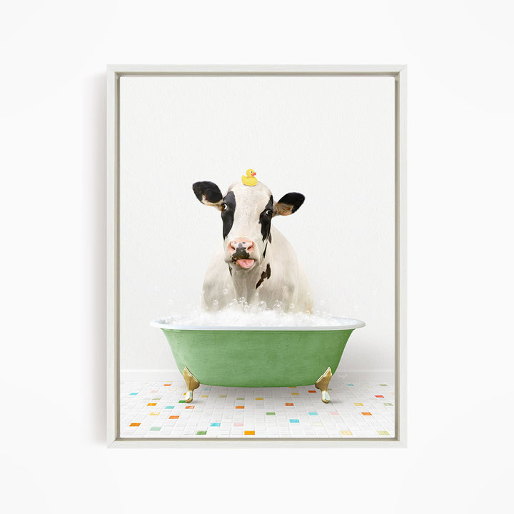 A black and white cow is sitting in a green bathtub filled with bubbles, with a yellow rubber duck perched on its head.