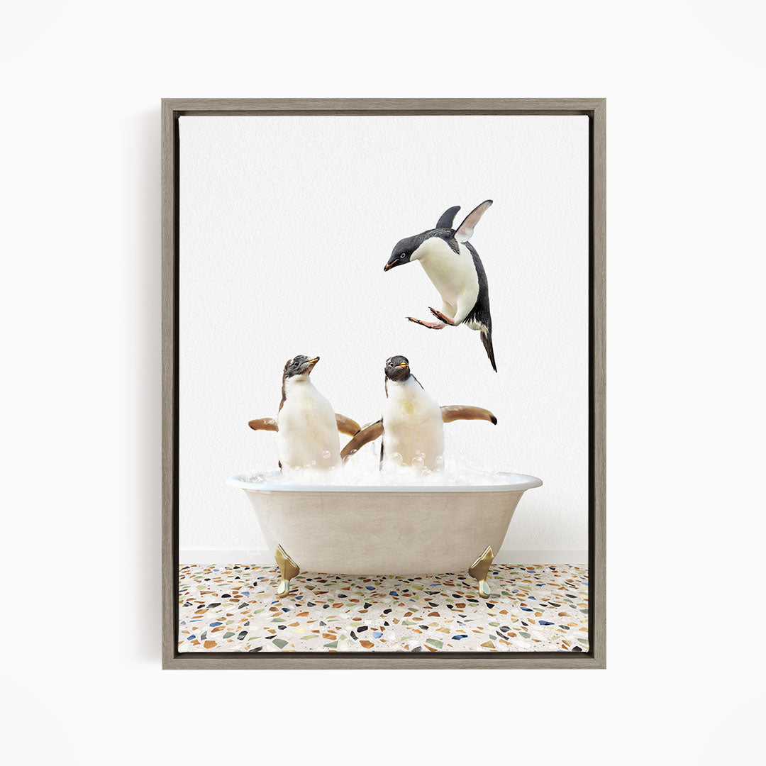 A framed image depicting two penguins standing in a bathtub filled with water, with one penguin flying towards the other.