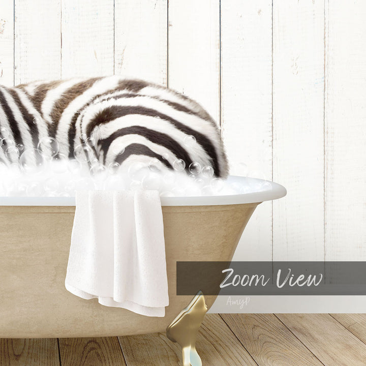 A zebra lying in a bathtub filled with bubbles, with a towel draped over the side.