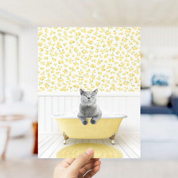 A gray cat sitting in a yellow bathtub filled with bubbles, surrounded by a yellow and white patterned wallpaper.