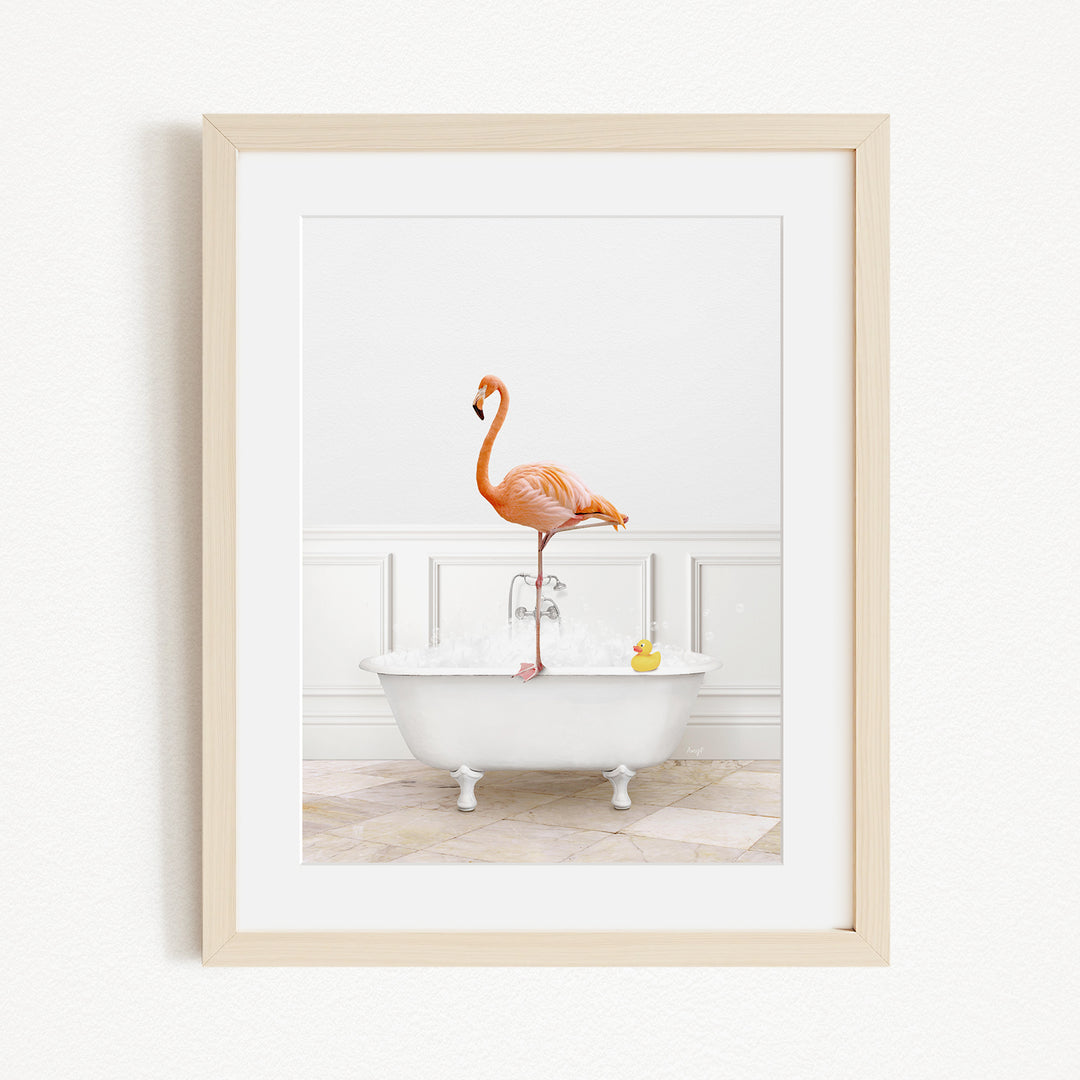 A framed image of a pink flamingo standing on the edge of a white bathtub filled with water and bubbles.