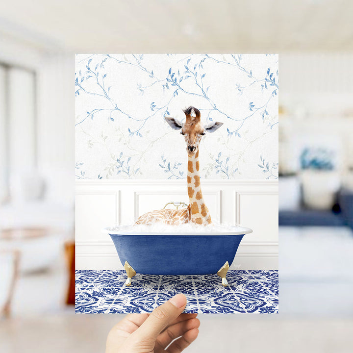 A giraffe sitting in a blue bathtub filled with bubbles, surrounded by a patterned blue and white rug.