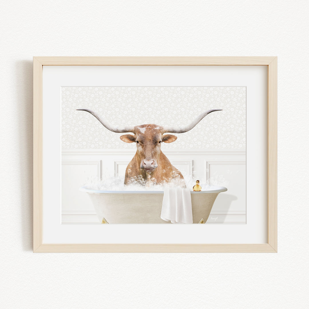 A framed image depicting a horned animal, likely a cow or a bull, sitting in a bathtub filled with bubbles.