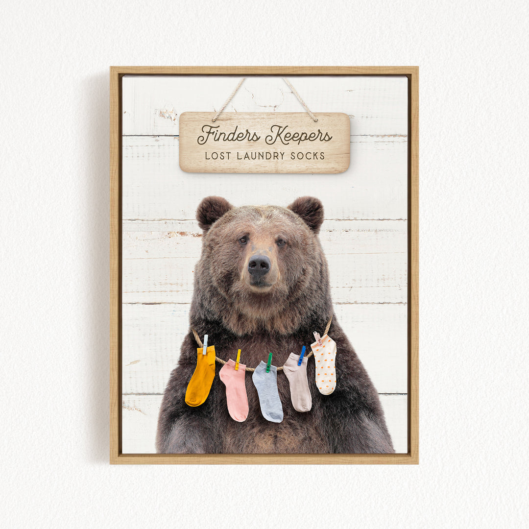 A wooden sign with the text "Finders Keepers" hangs above a bear wearing a variety of colorful socks.