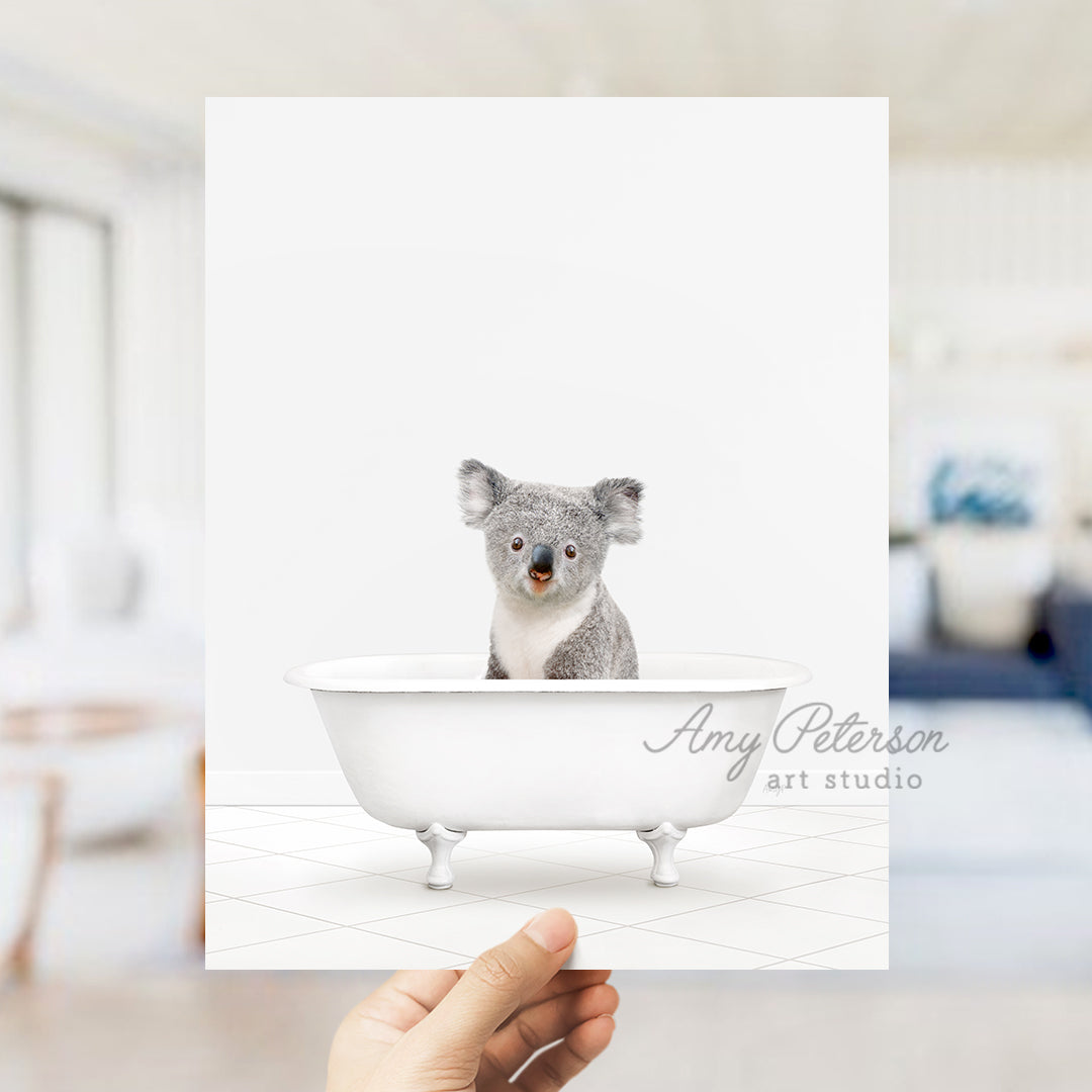 a hand holding a card with a koala in a bathtub