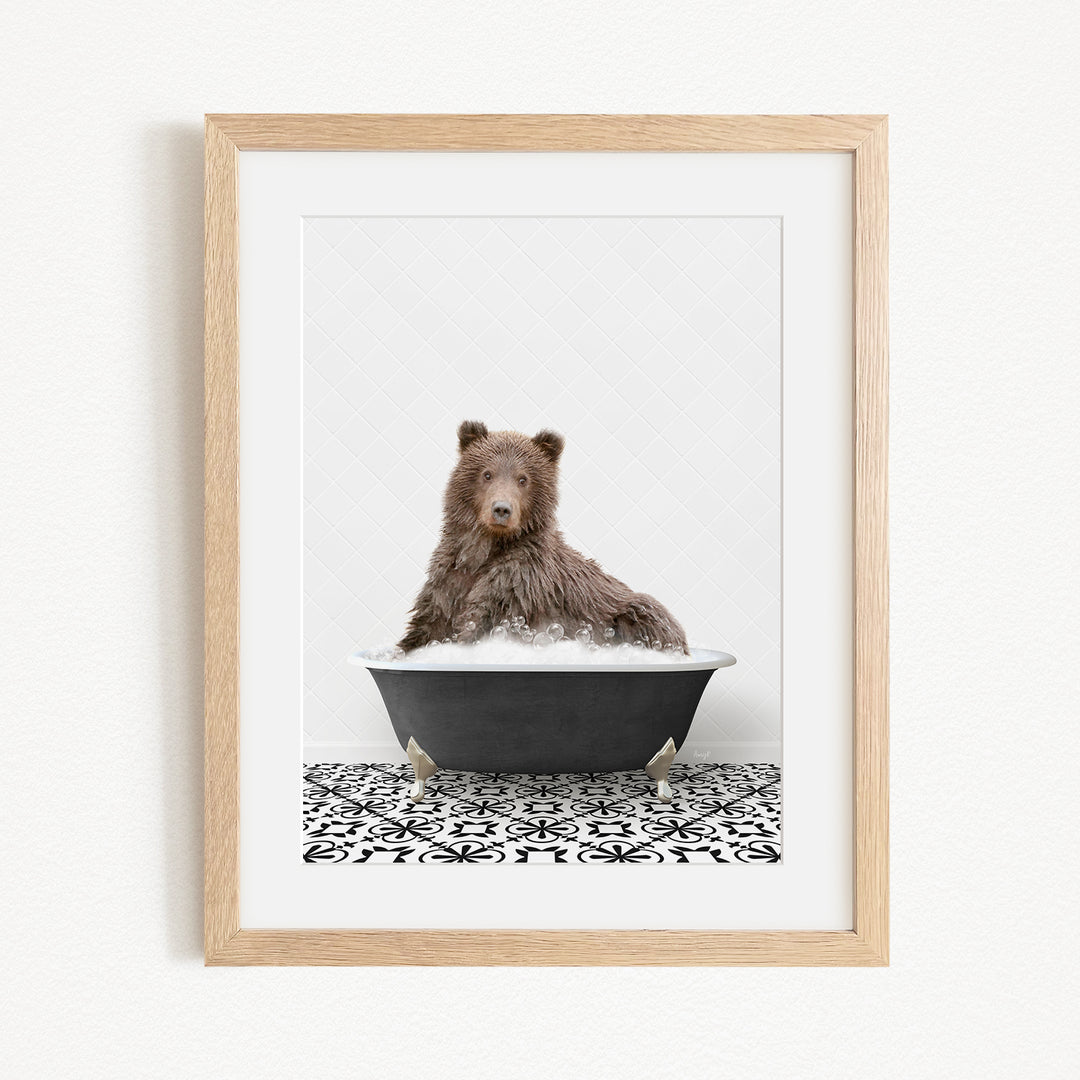 A brown bear sitting in a black bathtub filled with bubbles, surrounded by a black and white patterned floor.