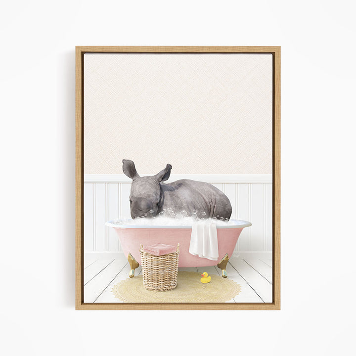 A rhinoceros is sitting in a pink bathtub filled with water, surrounded by a yellow rubber duck and a basket.
