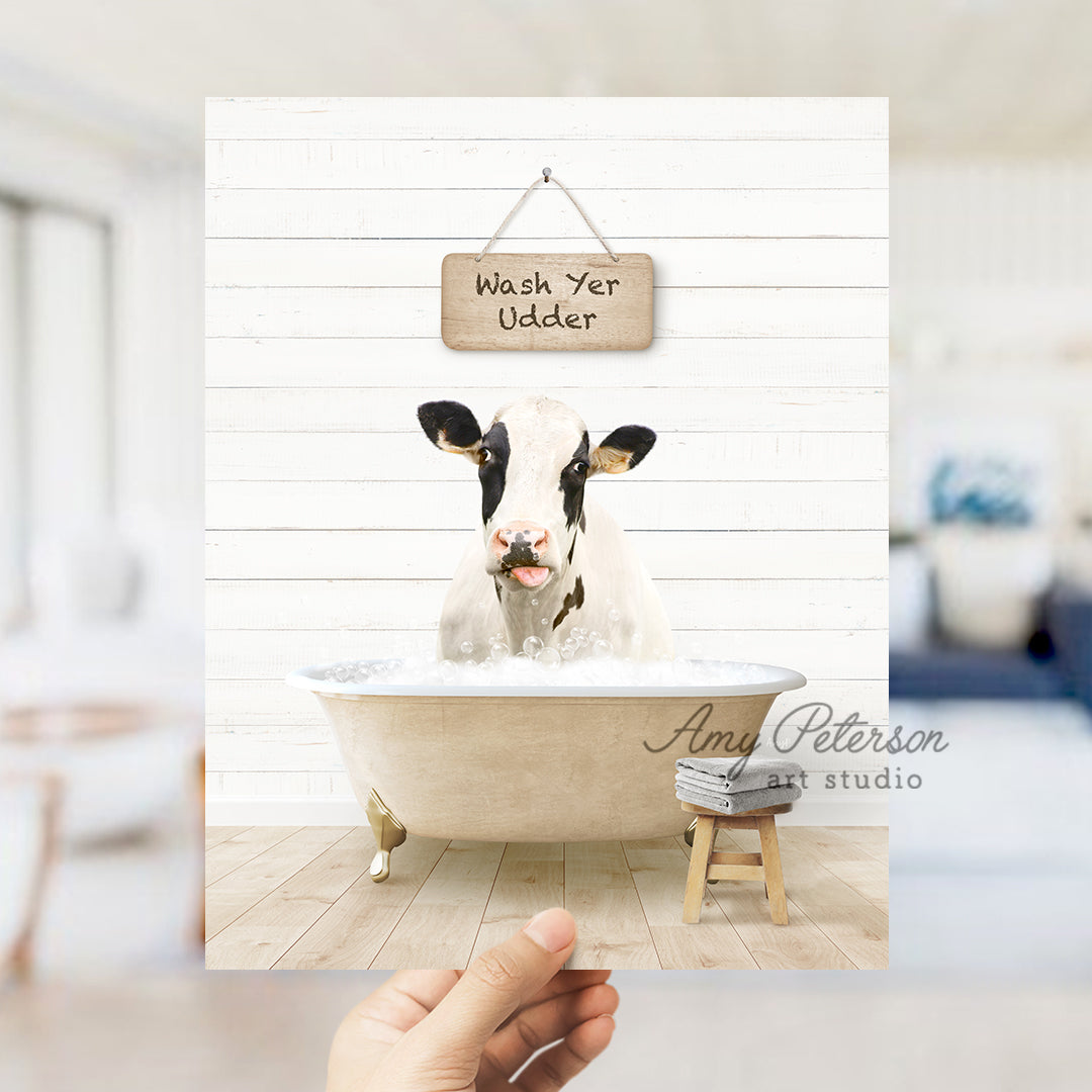 a hand holding up a photo of a cow in a bathtub