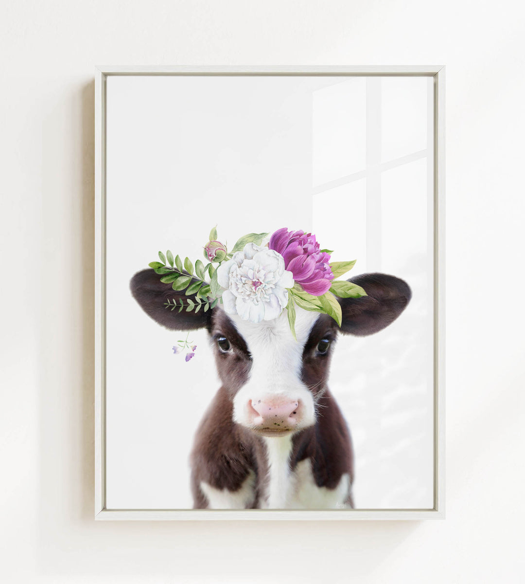 A framed image of a cow wearing a floral crown on its head.