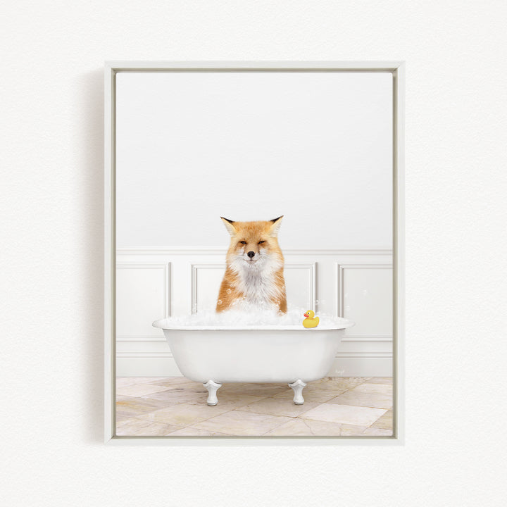A red fox is sitting in a white bathtub filled with bubbles, with a rubber duck floating in the water.