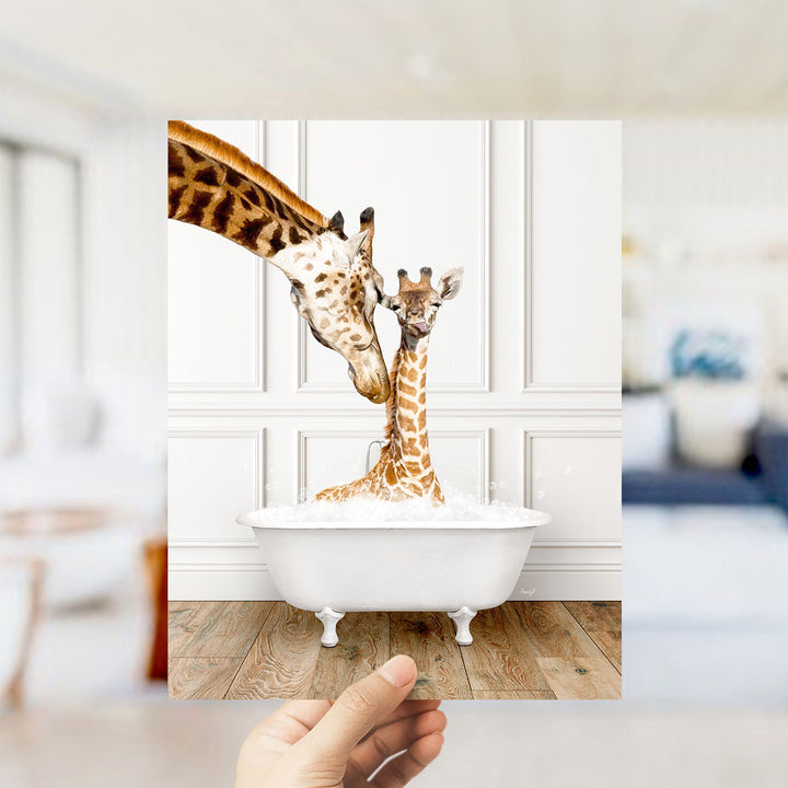 A mother giraffe and her baby giraffe are sitting together in a white bathtub, with the mother gently licking her baby.