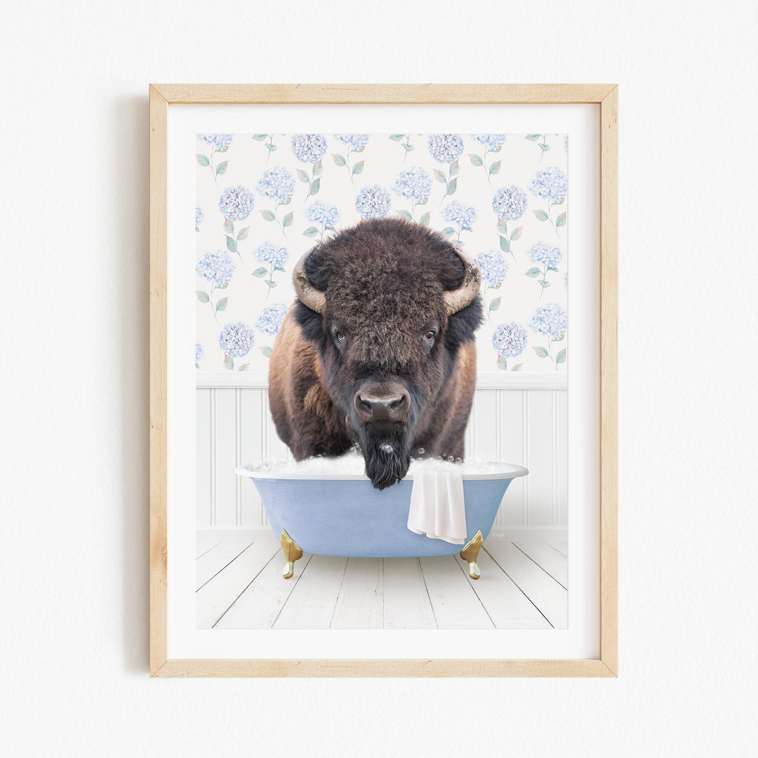 A buffalo is sitting in a blue bathtub, with a towel draped over the side of the tub.