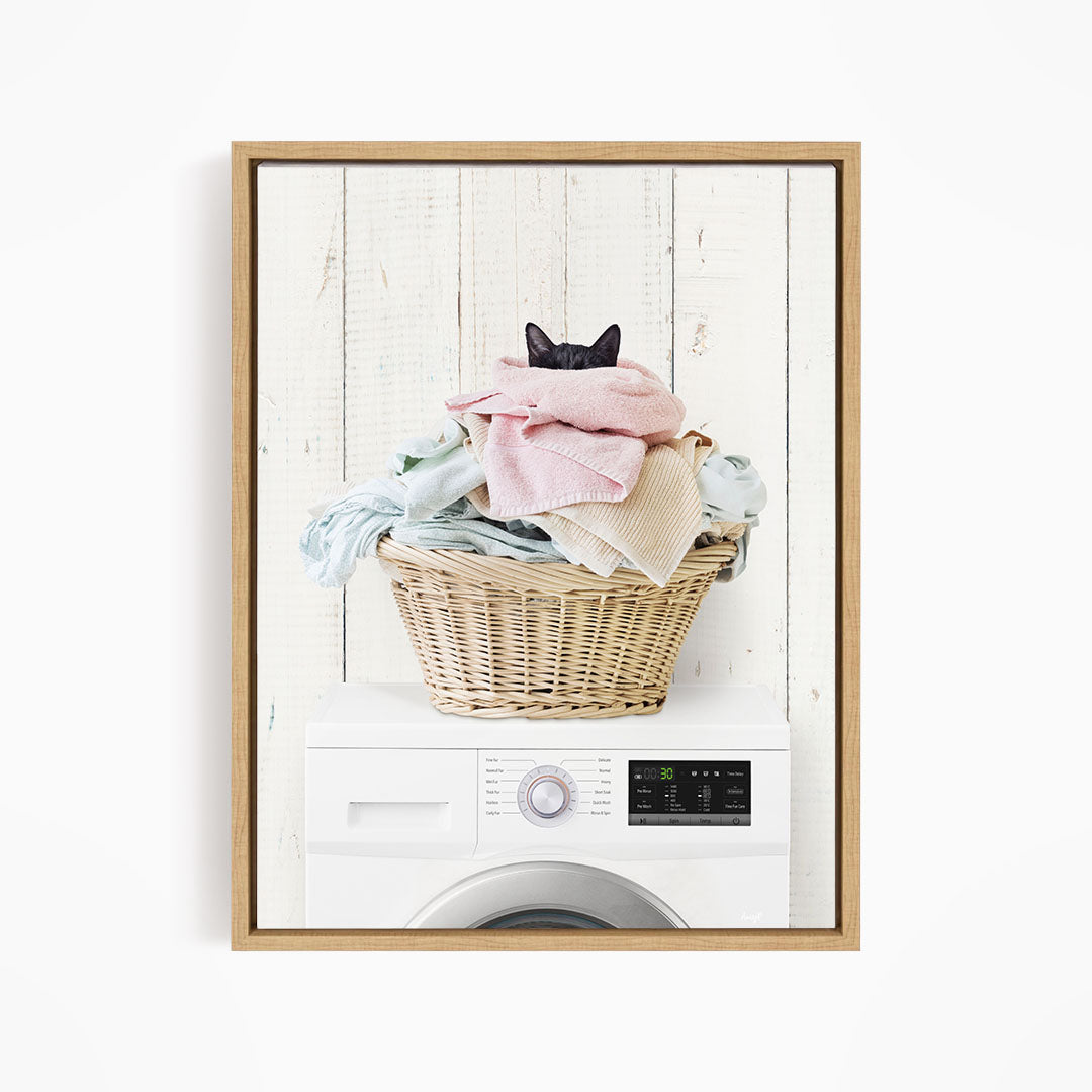 A cat is sitting on top of a basket filled with laundry, which is placed on top of a washing machine.