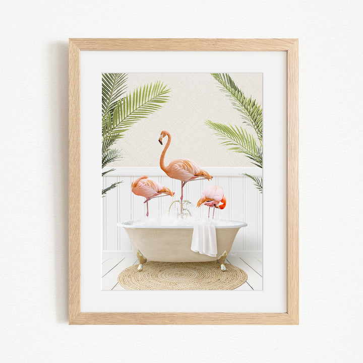 A framed image depicting three flamingos standing in a bathtub filled with water, surrounded by green plants.