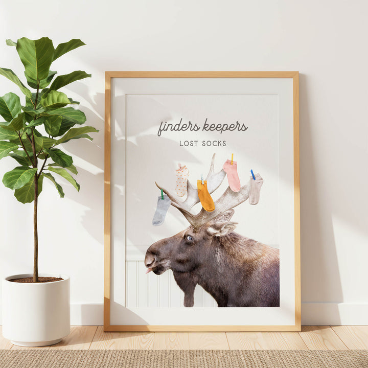 a framed poster with a moose's head and antlers, along with the text "finders keepers" and "lost socks" written on it.
