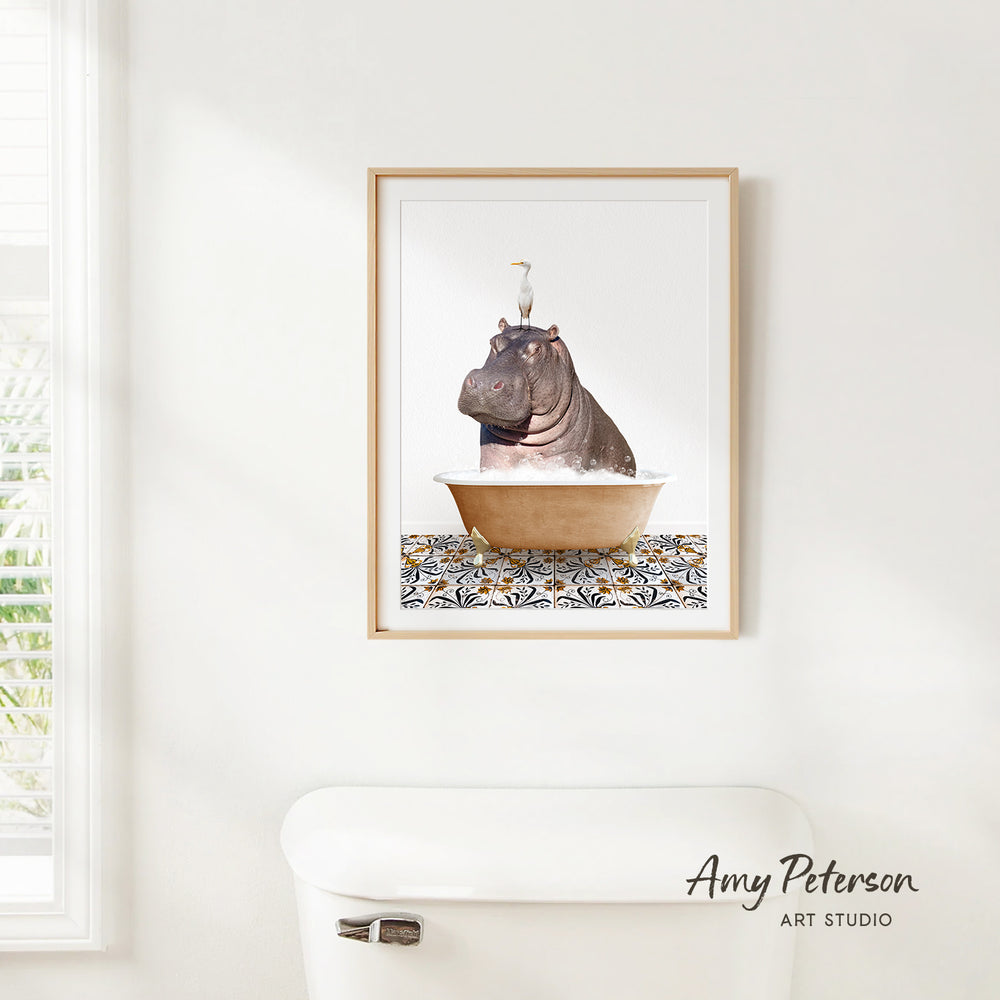 A framed image of a hippopotamus sitting in a bathtub, with a bird perched on its head, is hanging on a white wall.