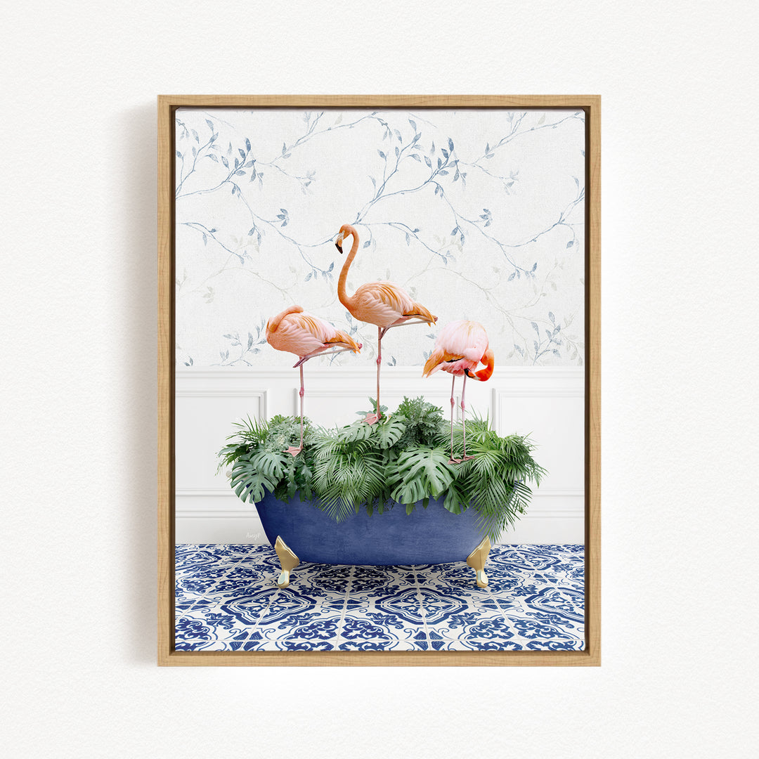 A framed image depicting three pink flamingos standing in a blue bathtub filled with green plants, set against a white wall with a blue and white patterned wallpaper.