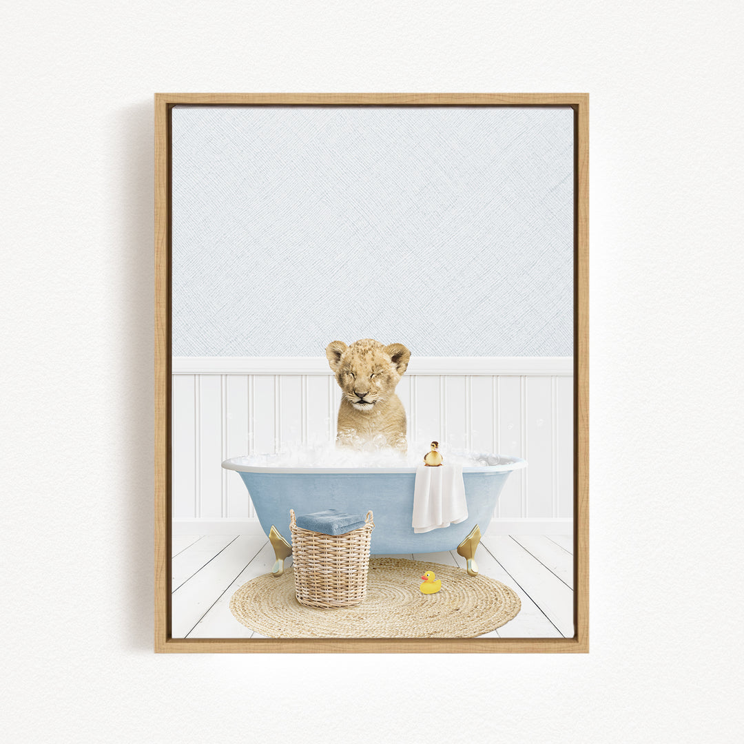 A young lion cub sitting in a blue bathtub filled with bubbles, surrounded by a basket of toys and a yellow rubber duck.