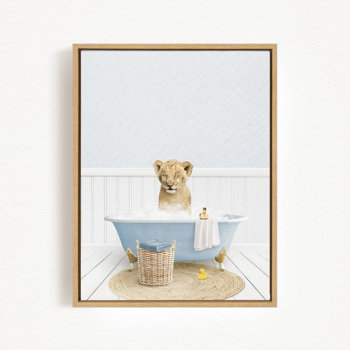 A young lion cub sitting in a blue bathtub filled with bubbles, surrounded by a basket of toys and a yellow rubber duck.