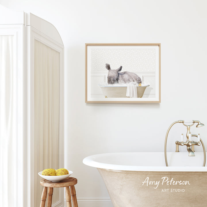 a bathroom with a white bathtub, a framed picture of a rabbit in a bathtub, and a wooden stool with a bowl of fruit.