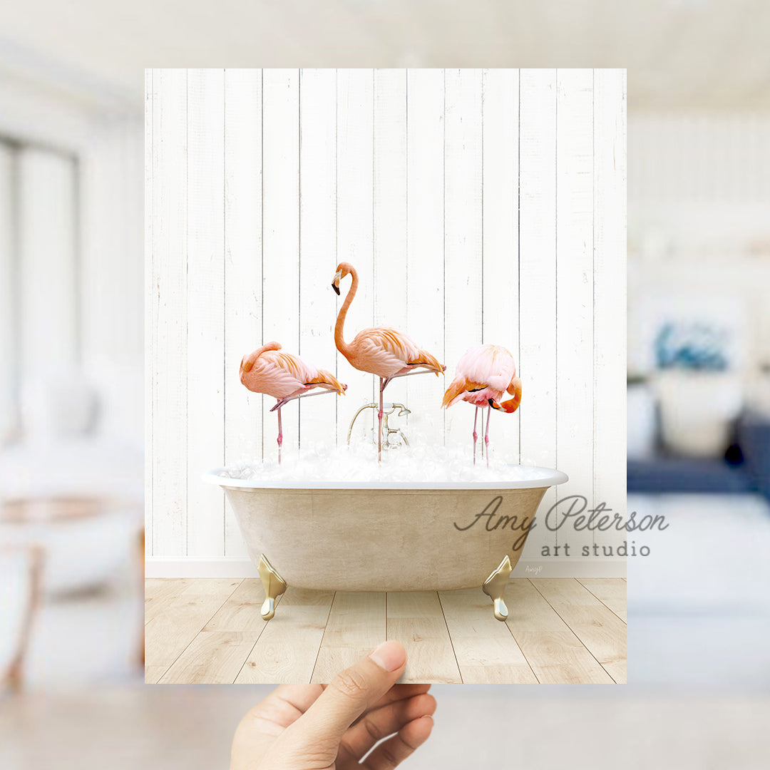 a person holding up a photo of three flamingos in a bathtub