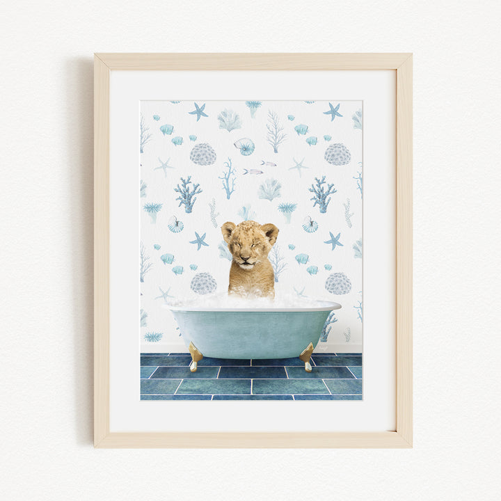 A young lion cub sitting in a bathtub filled with bubbles, surrounded by a blue and white ocean-themed wallpaper.