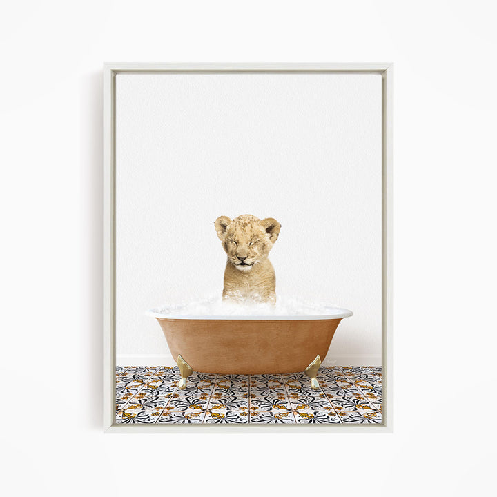 A young lion cub sitting in a bathtub filled with water, looking up at the camera.