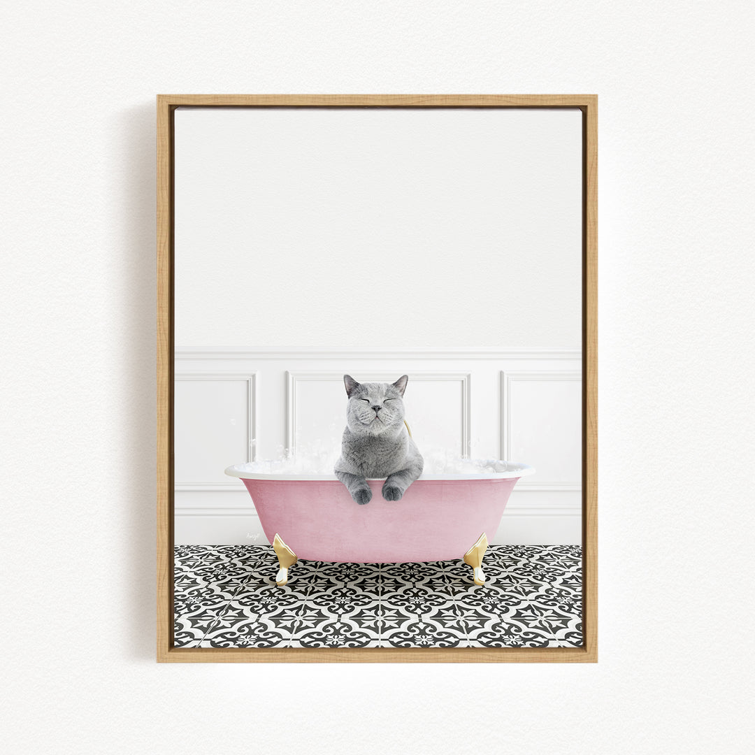 A gray cat sitting in a pink bathtub filled with bubbles, with a black and white patterned floor beneath it.