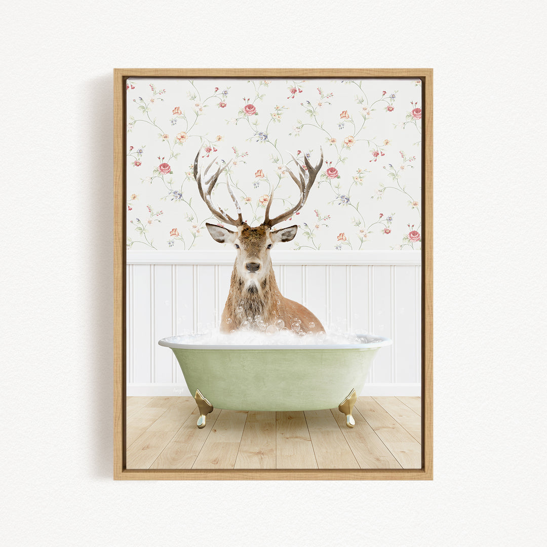 A deer with large antlers is sitting in a green bathtub filled with bubbles, against a floral wallpaper background.