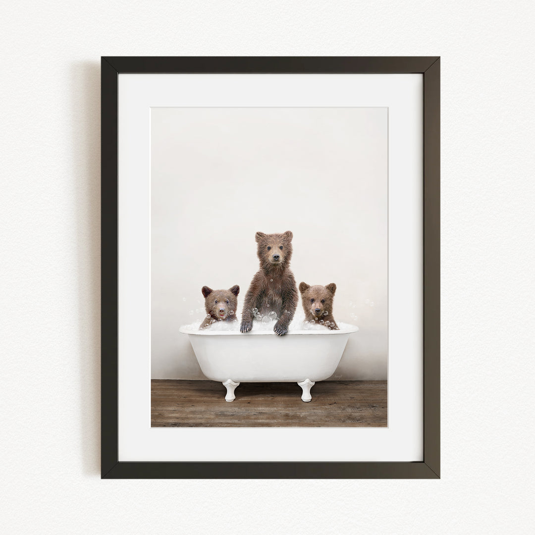 A framed image depicting three brown bears sitting in a white bathtub, with one bear sitting in the center and the other two bears sitting on either side.