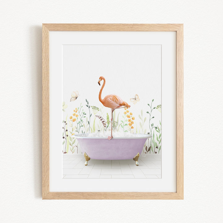 A framed illustration depicting a pink flamingo standing on a purple bathtub filled with bubbles, surrounded by a garden scene with flowers and butterflies.