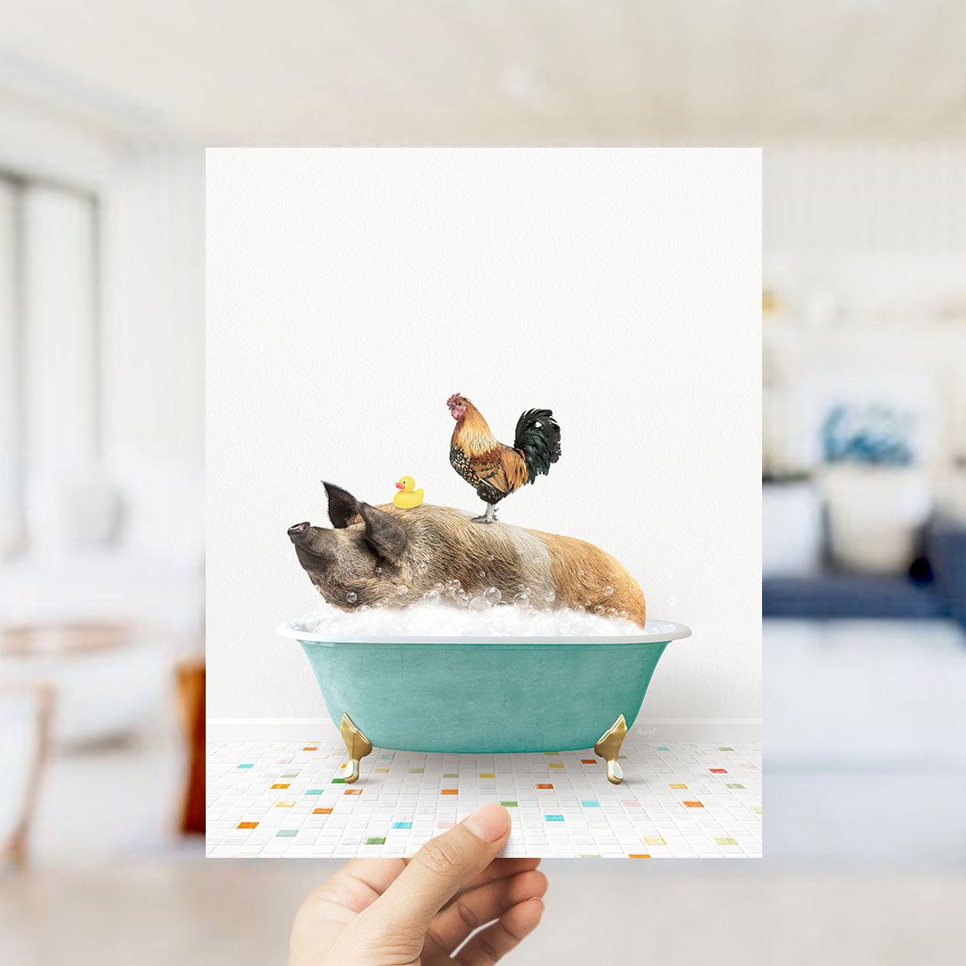 A hand holds up a framed image depicting a pig sitting in a bathtub, with a rooster perched on its back.