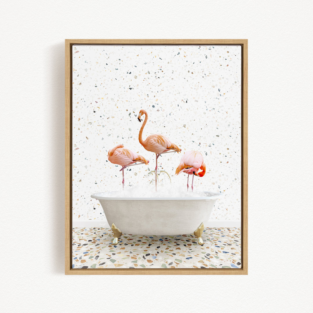 A framed image depicting three flamingos standing in a white bathtub filled with water, surrounded by a speckled tile floor.